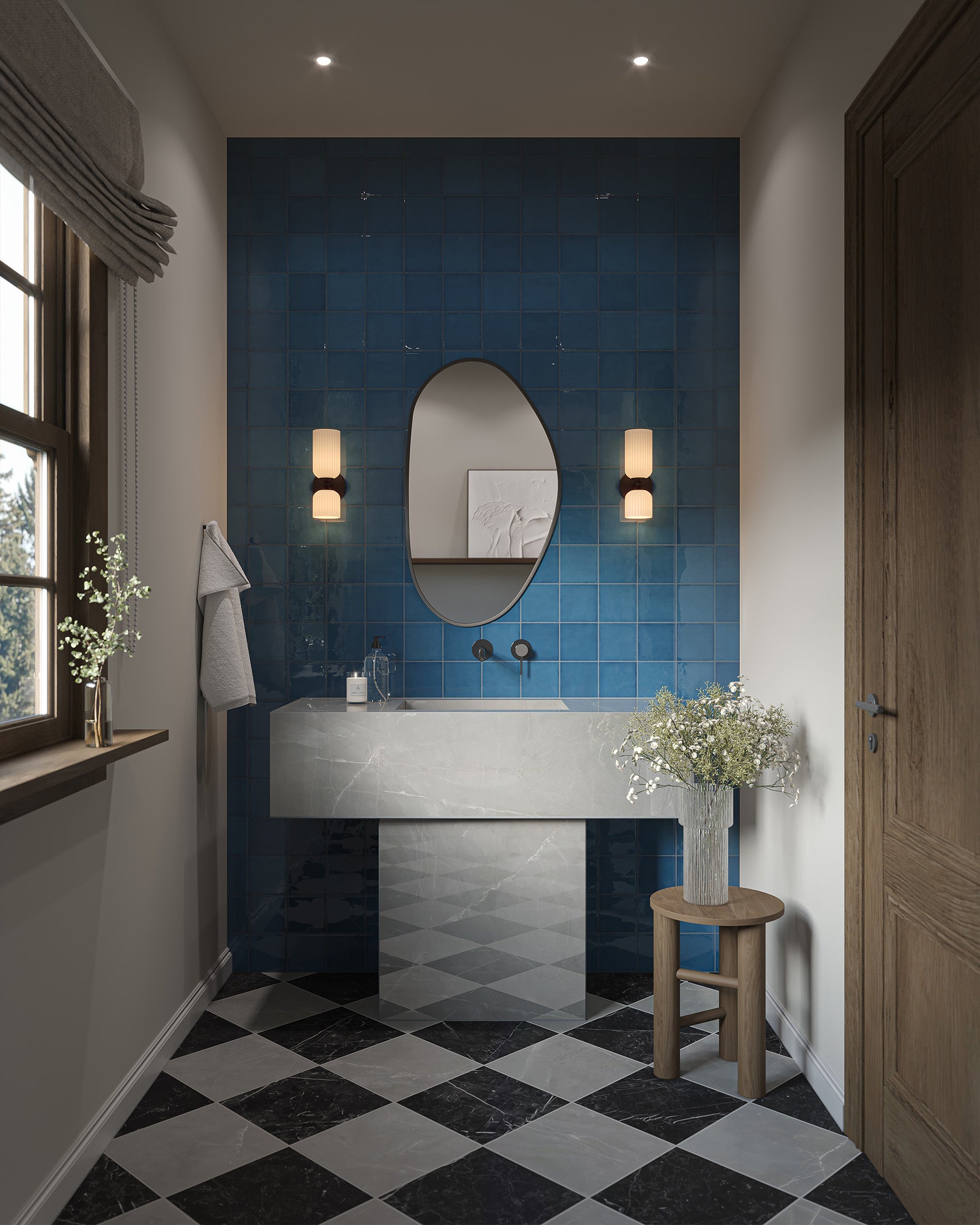 Pair of ribbed glass vanity lights mounted beside an oval mirror on deep blue ceramic tiles, lighting a marble sink with checkered floor tiles in a modern bathroom.