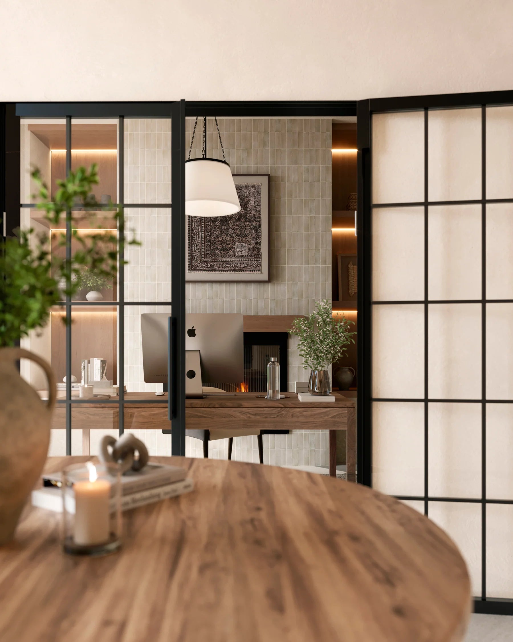 Modern home office with a wood desk, light sage vertical tiles, warm shelf lighting, and black-framed glass doors for a sleek, airy feel.