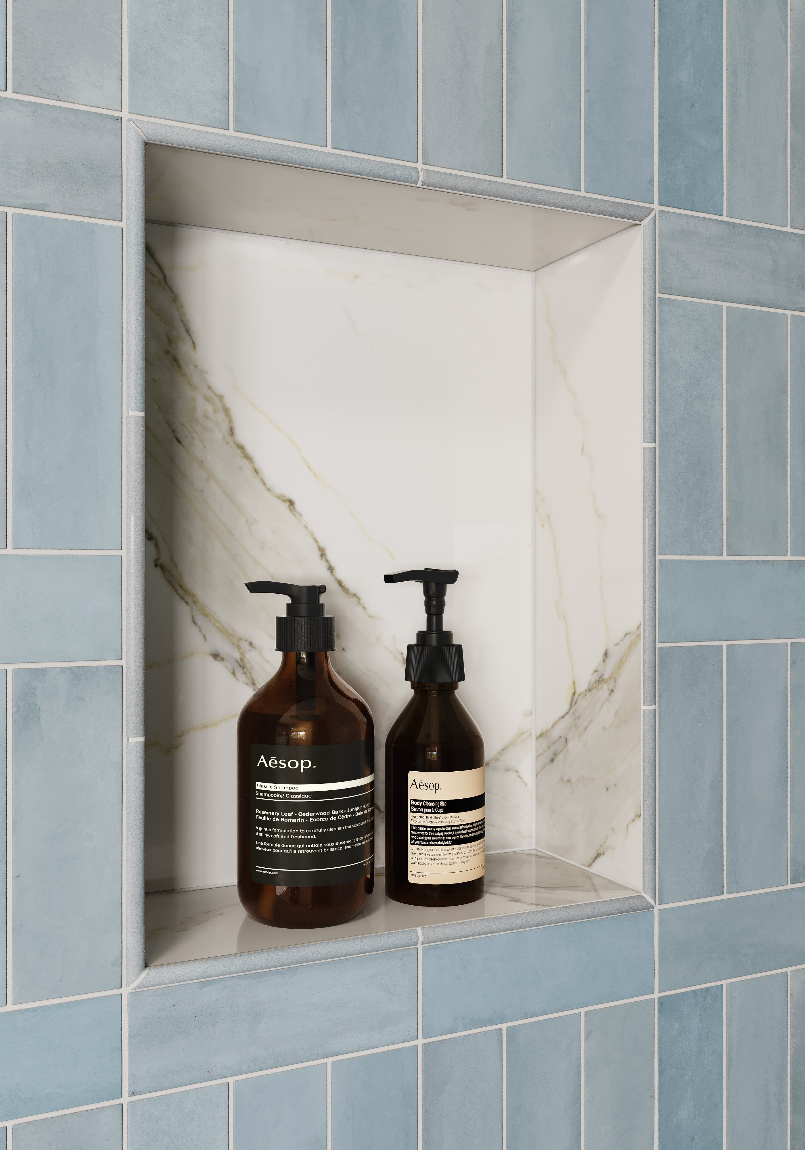 Shower niche with a marble interior framed by glossy pastel blue subway tiles and rounded tile edge trim, holding two amber pump bottles