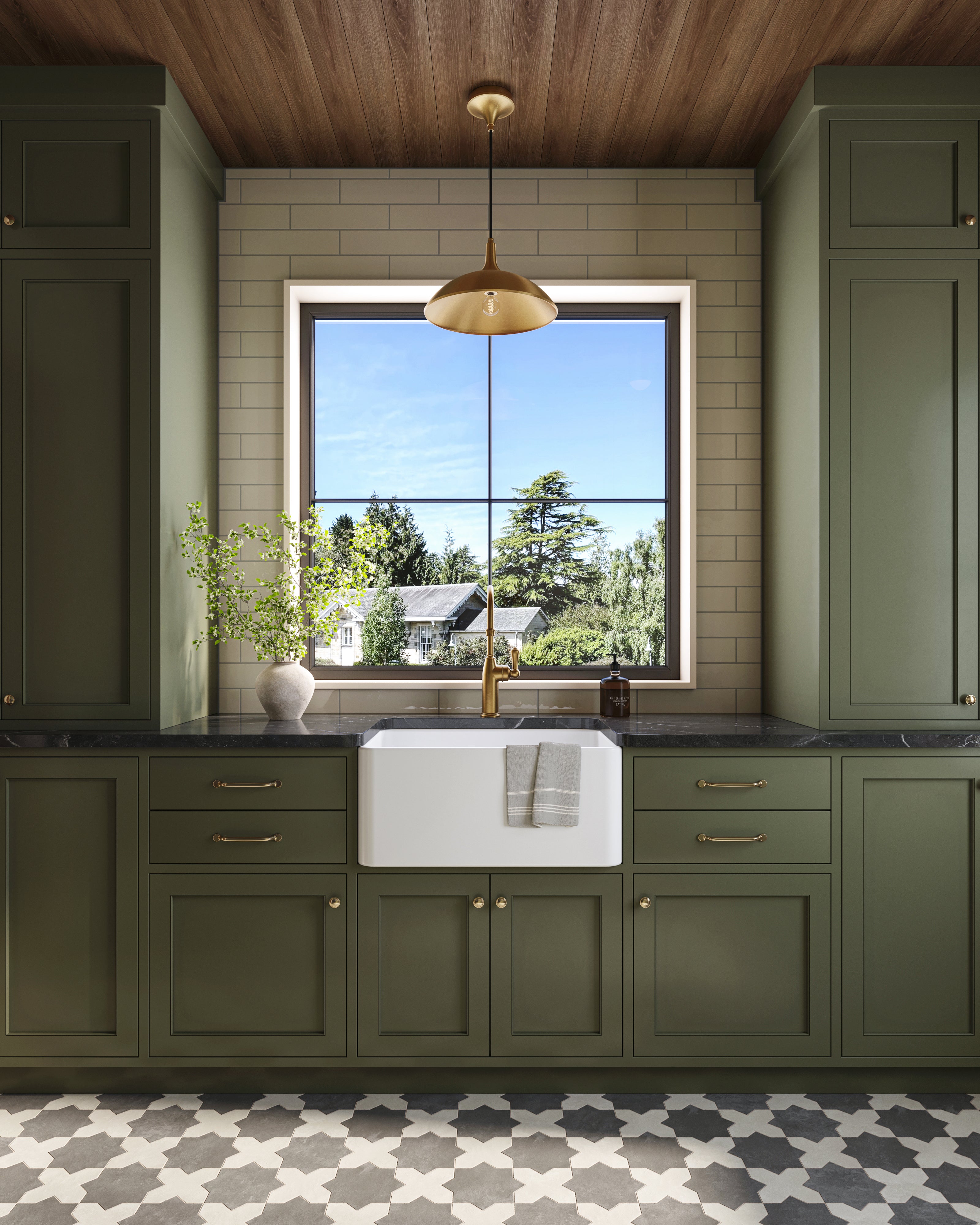 Green kitchen cabinets with farmhouse sink, brass faucet, patterned tile floor, and brushed gold pendant centered above the window