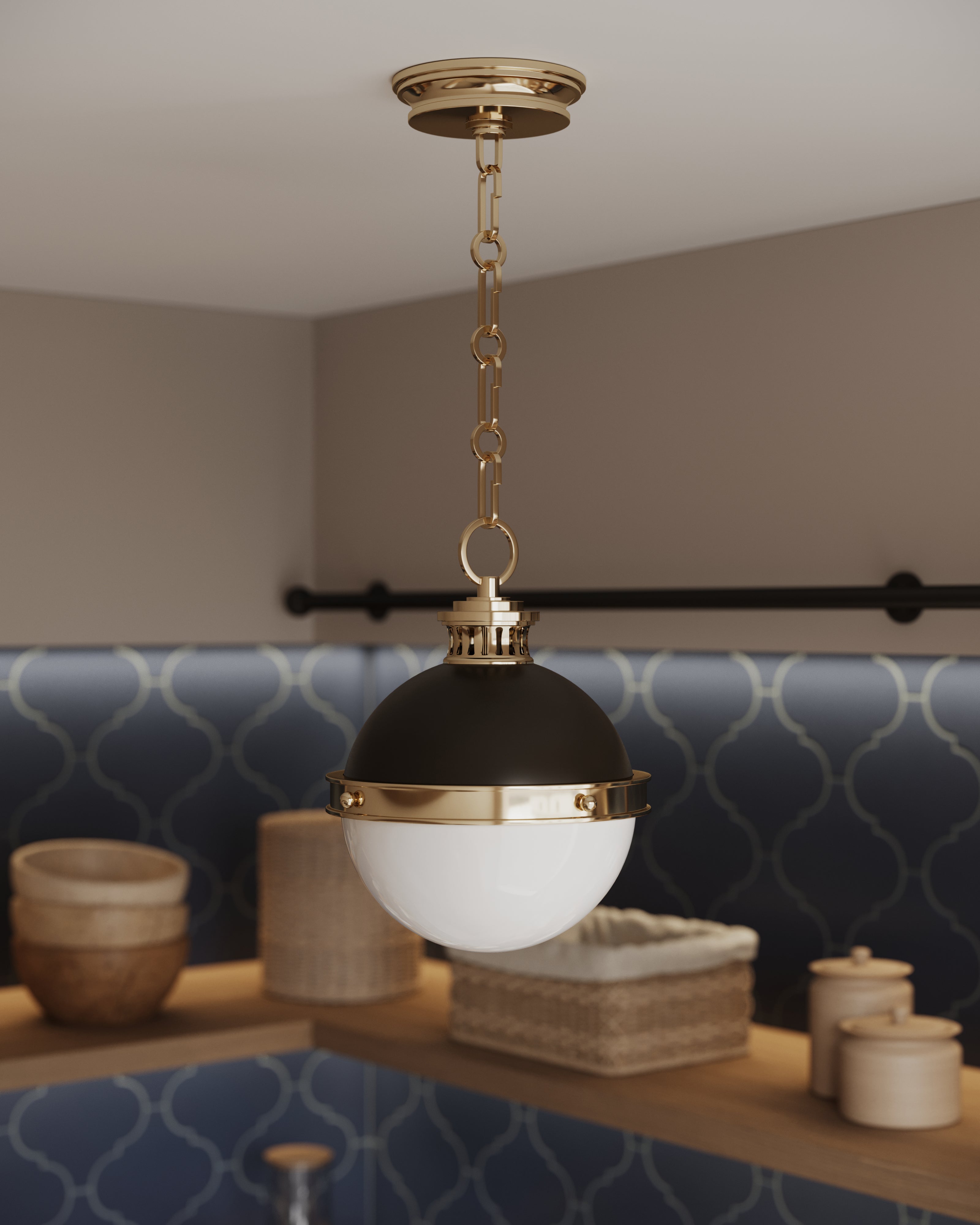 Compact globe pendant light with an aged brass chain, dark metal cap, and white glass shade hanging above open shelving in a modern kitchen.