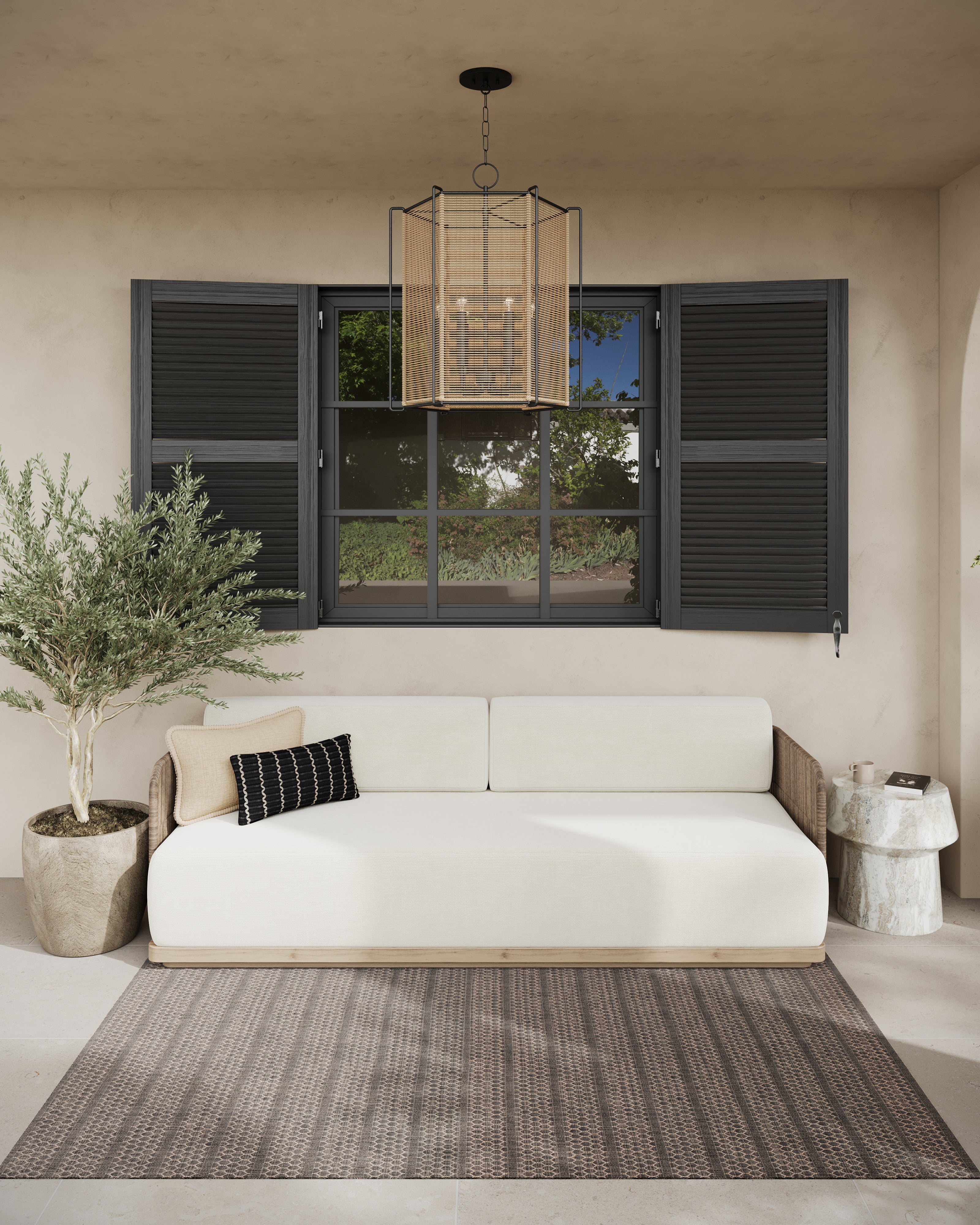 Black and tan accent pillows rest on a neutral sofa, mixing stitched and woven textures within a calm patio setting framed by shutters and natural elements.