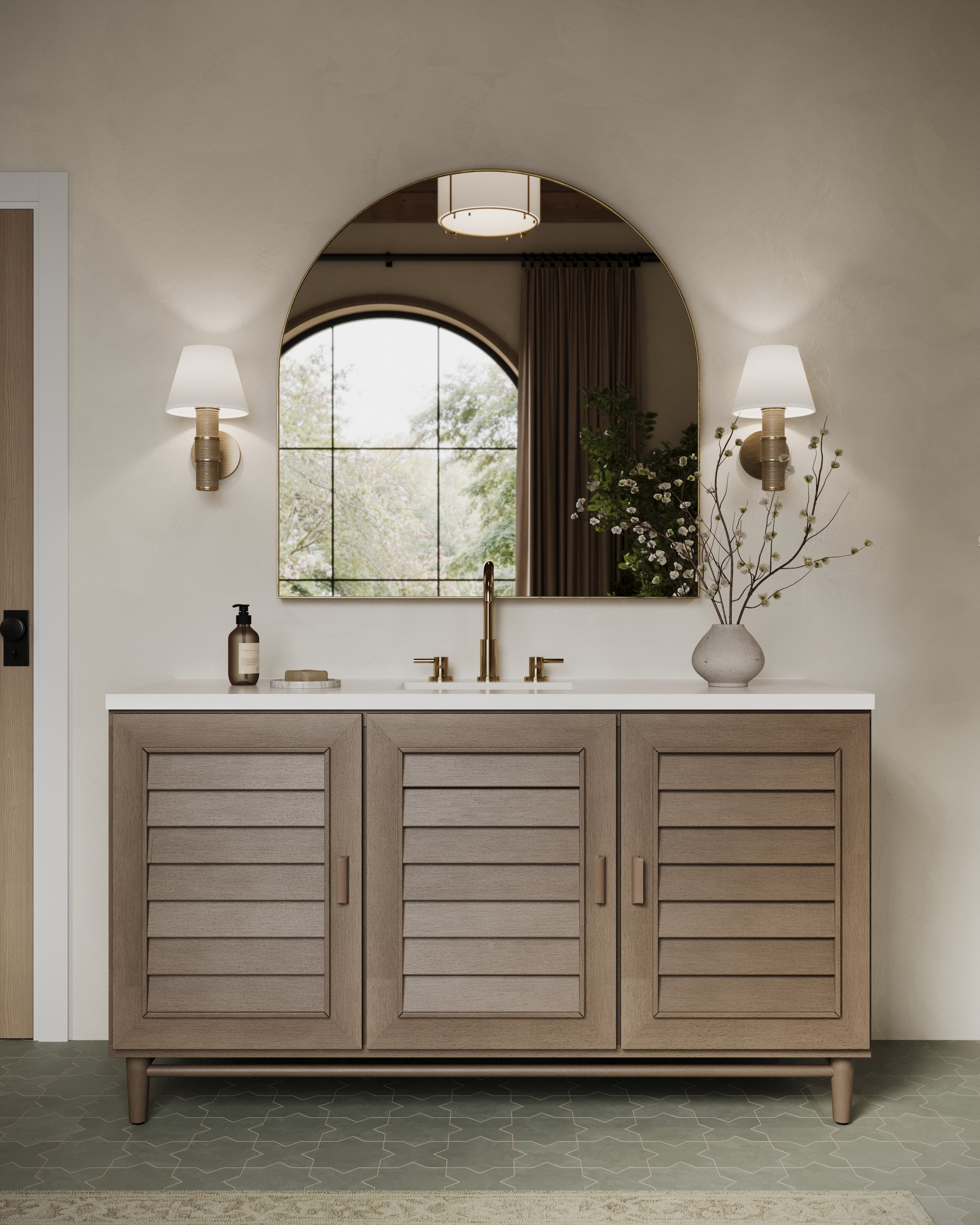 Bathroom vanity with light wood cabinet, patina brass sconces with white shades, arched mirror, and soft neutral design accents.