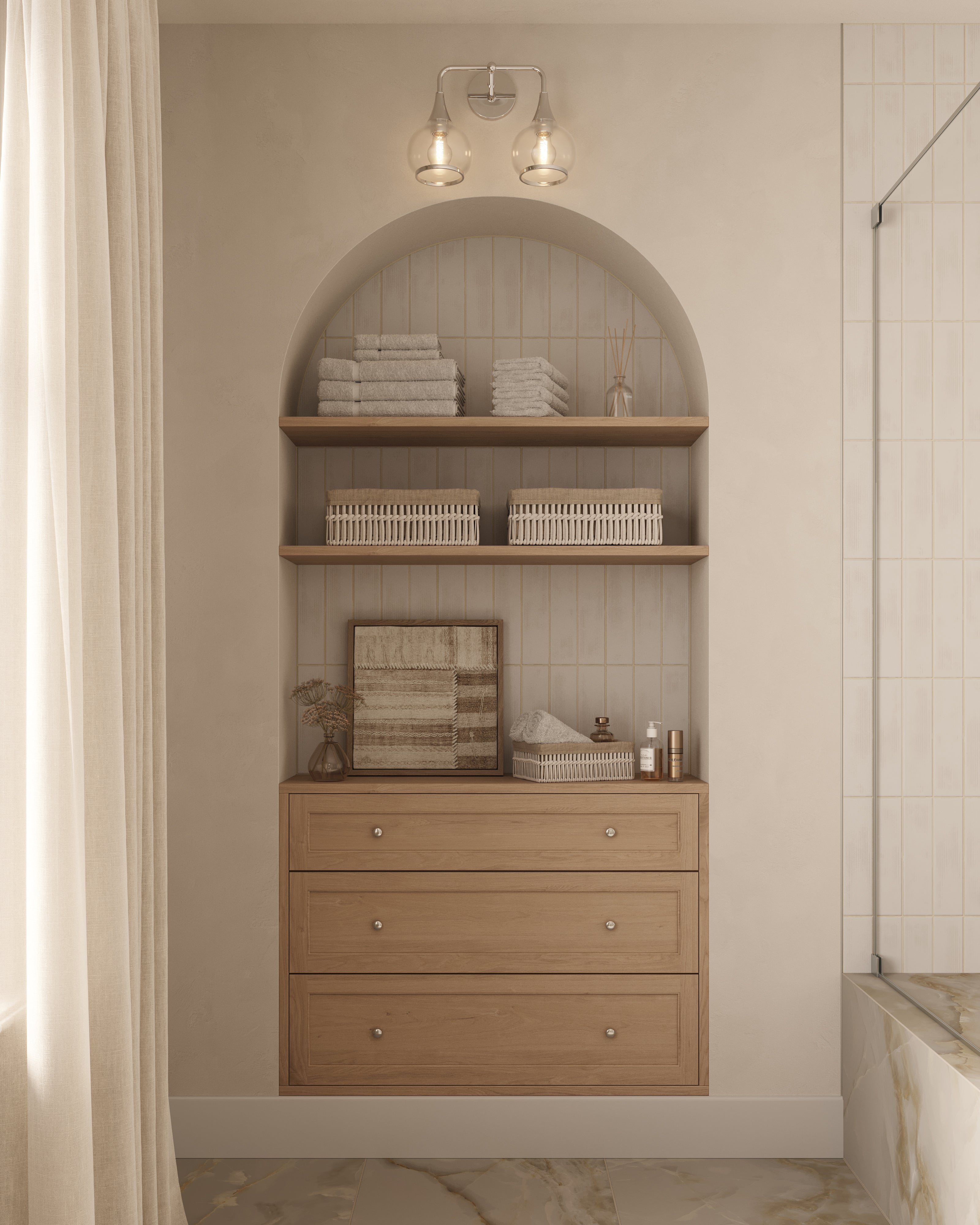 Chrome double wall sconce with clear glass globe shades mounted above an arched recessed shelf with wooden drawers and neatly stacked towels.